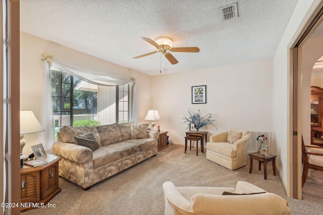 carpeted living room featuring ceiling fan and a textured ceiling