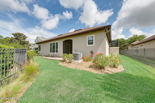 rear view of property featuring a yard and central AC