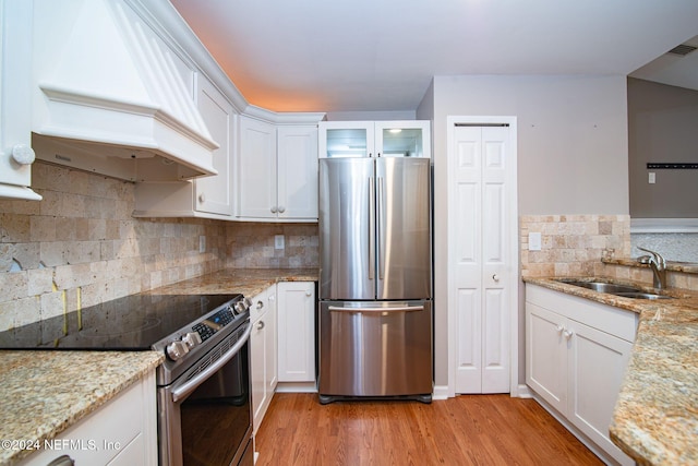 kitchen featuring stainless steel appliances, white cabinetry, light hardwood / wood-style floors, and custom exhaust hood