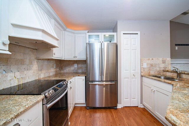 300 Sandiron Cir Unit 333, Ponte Vedra Beach, FL 32082 - kitchen featuring stainless steel appliances, custom range hood, white cabinetry, light wood-type flooring, and light stone countertops