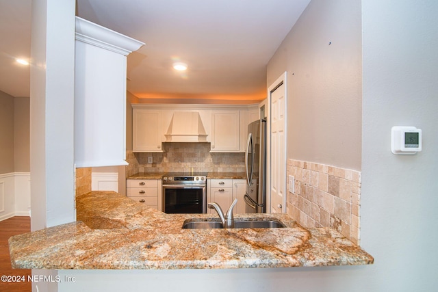 300 Sandiron Cir Unit 333, Ponte Vedra Beach, FL 32082 - kitchen with custom exhaust hood, appliances with stainless steel finishes, wainscoting, light stone countertops, and a peninsula