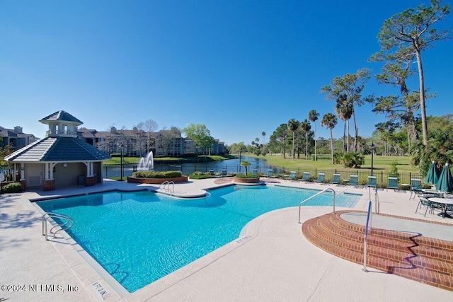 view of swimming pool featuring a patio and a water view