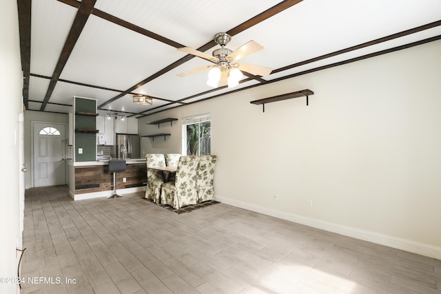 unfurnished living room with ceiling fan, sink, beamed ceiling, and light hardwood / wood-style floors