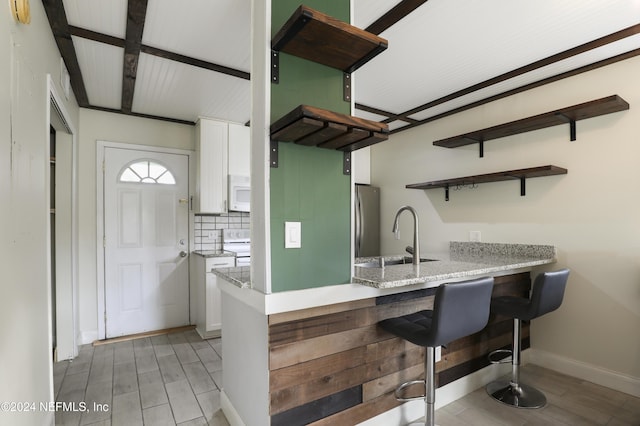 kitchen featuring beam ceiling, sink, backsplash, white appliances, and white cabinets