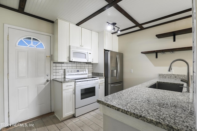 kitchen with white appliances, sink, beam ceiling, dark stone countertops, and white cabinetry