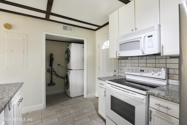 kitchen featuring white cabinetry, white appliances, stacked washer / dryer, and dark stone counters