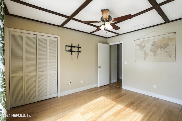 unfurnished bedroom with beam ceiling, a closet, light hardwood / wood-style floors, and ceiling fan