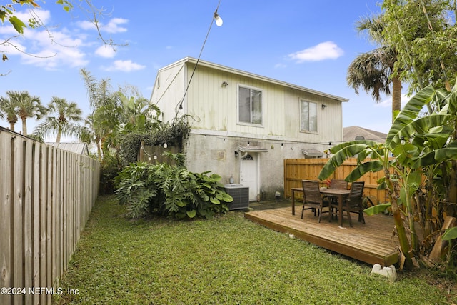 rear view of house featuring a lawn, central air condition unit, and a deck