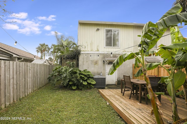 back of house with a lawn, cooling unit, and a wooden deck