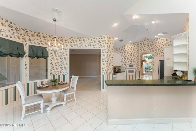 kitchen featuring hanging light fixtures, lofted ceiling, kitchen peninsula, and stainless steel refrigerator