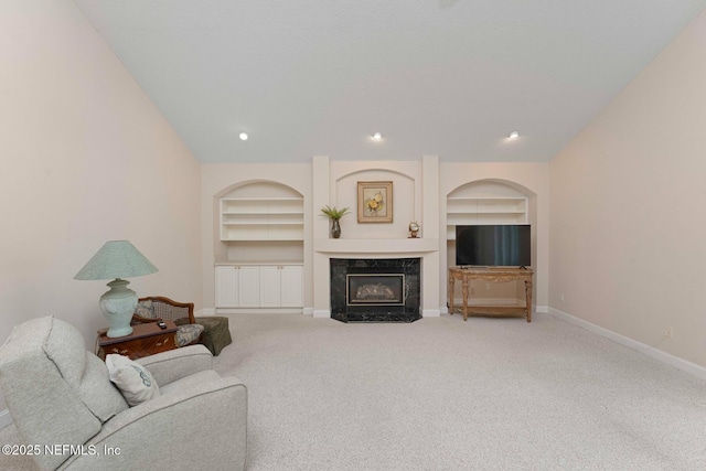 living room featuring carpet floors, built in shelves, and a high end fireplace