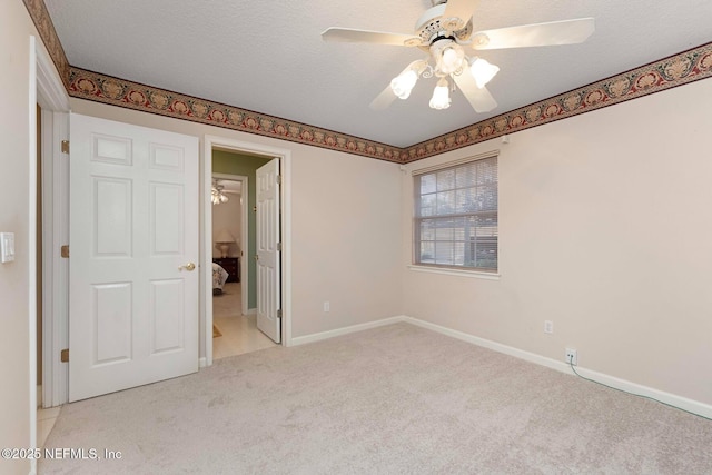 unfurnished bedroom featuring ceiling fan, light colored carpet, and a textured ceiling