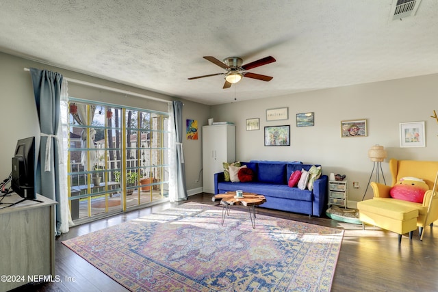 living room with ceiling fan, dark wood-type flooring, and a textured ceiling