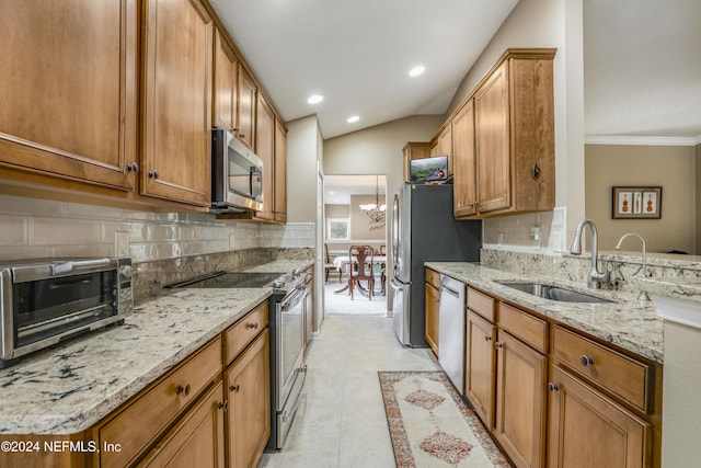 kitchen with sink, tasteful backsplash, light stone counters, vaulted ceiling, and appliances with stainless steel finishes