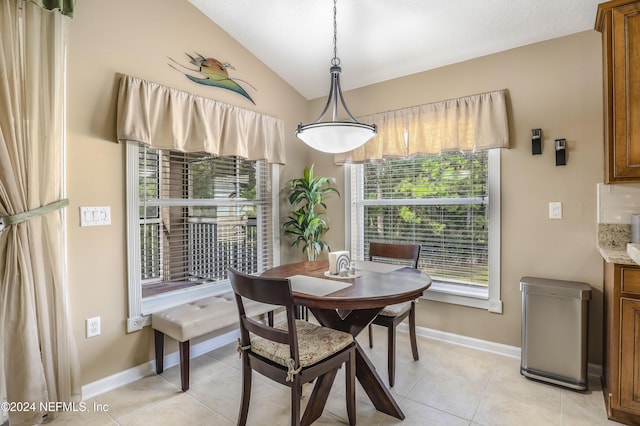 tiled dining space featuring vaulted ceiling