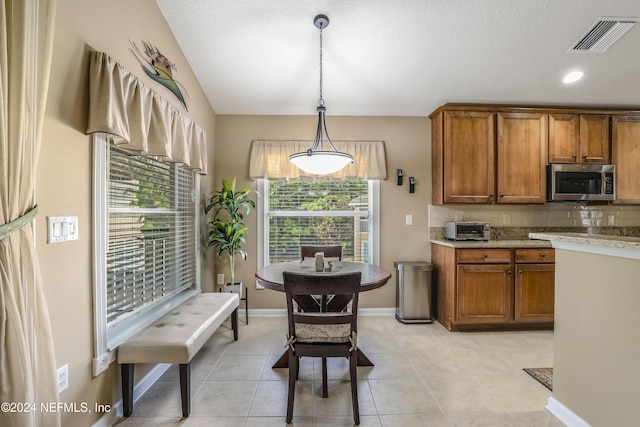 kitchen with decorative backsplash, pendant lighting, and light tile patterned floors