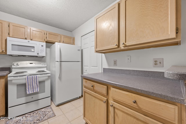 kitchen with light brown cabinetry, white appliances, a textured ceiling, and light tile patterned floors