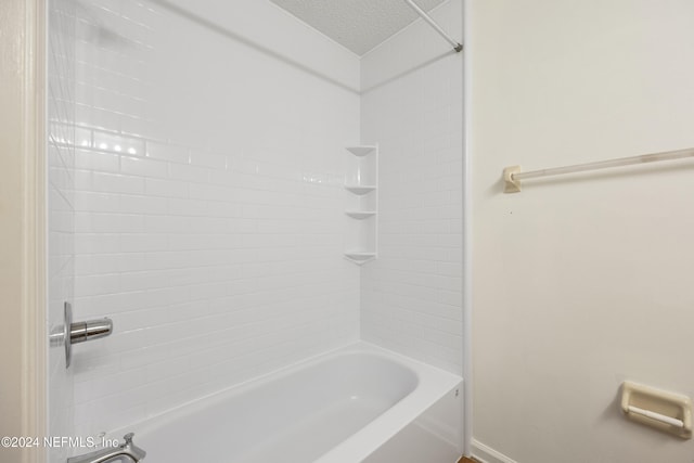 bathroom with a textured ceiling and tiled shower / bath combo