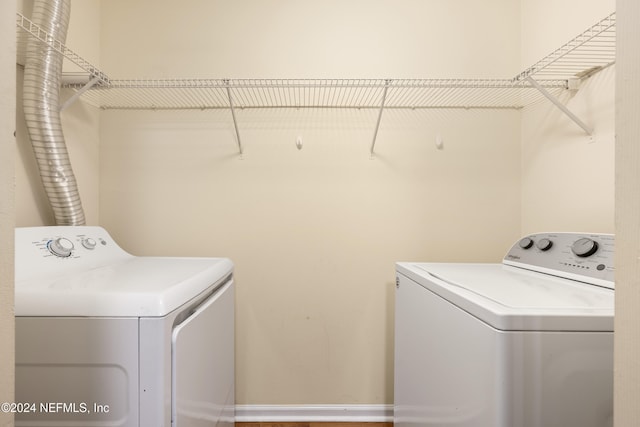 laundry area with washing machine and clothes dryer and hardwood / wood-style floors