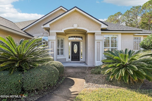 doorway to property with roof with shingles and stucco siding