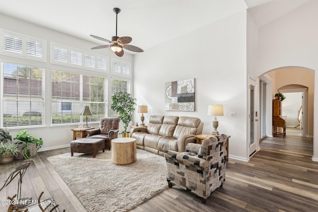 living room featuring arched walkways, wood finished floors, a wealth of natural light, and baseboards