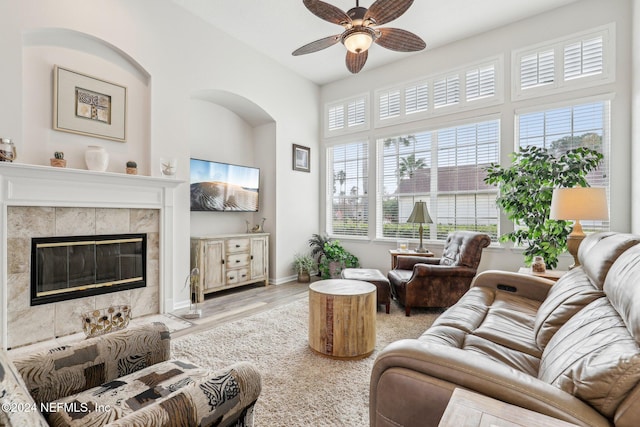 living room featuring a ceiling fan, a tile fireplace, baseboards, and wood finished floors