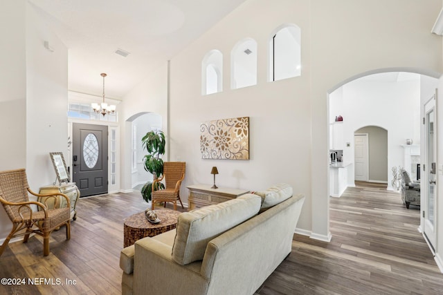 entryway with a notable chandelier, wood finished floors, visible vents, baseboards, and a towering ceiling