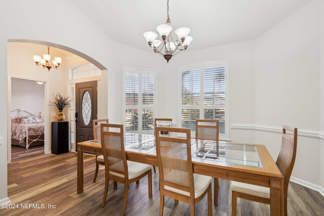 dining room with arched walkways, wood finished floors, and an inviting chandelier