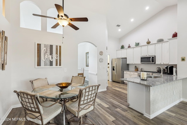 dining room featuring high vaulted ceiling, ceiling fan, arched walkways, and dark wood-type flooring