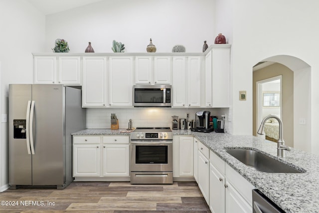 kitchen featuring appliances with stainless steel finishes, white cabinetry, a sink, and backsplash