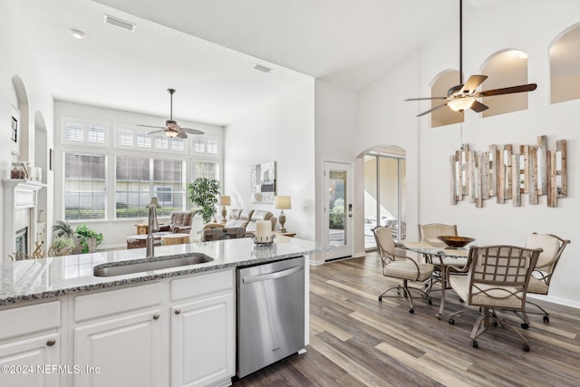 kitchen with arched walkways, visible vents, stainless steel dishwasher, white cabinetry, and a sink