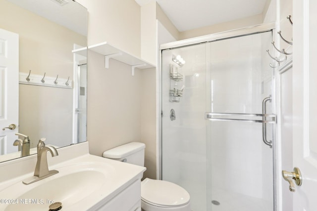 bathroom with toilet, a stall shower, and vanity