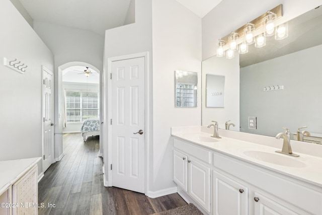 full bath with double vanity, ceiling fan, a sink, and wood finished floors