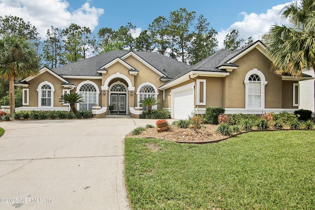 view of front of house featuring a front lawn, concrete driveway, stucco siding, french doors, and an attached garage