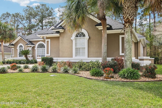 view of front facade with stucco siding, a shingled roof, and a front lawn