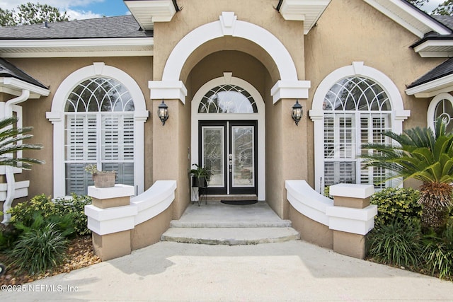 doorway to property with stucco siding and a shingled roof