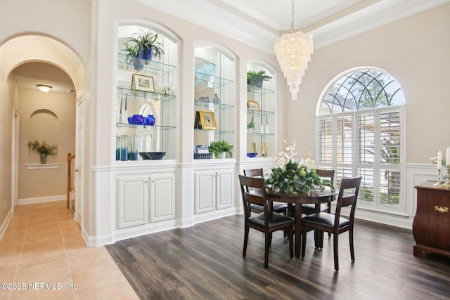 dining area with a notable chandelier, wood finished floors, arched walkways, and ornamental molding