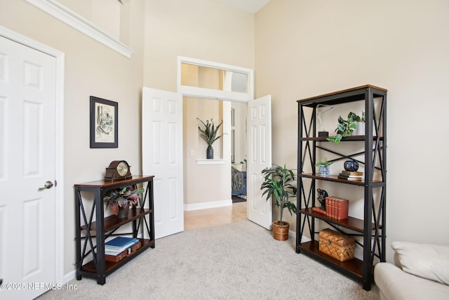 living area with tile patterned floors, a high ceiling, baseboards, and carpet floors