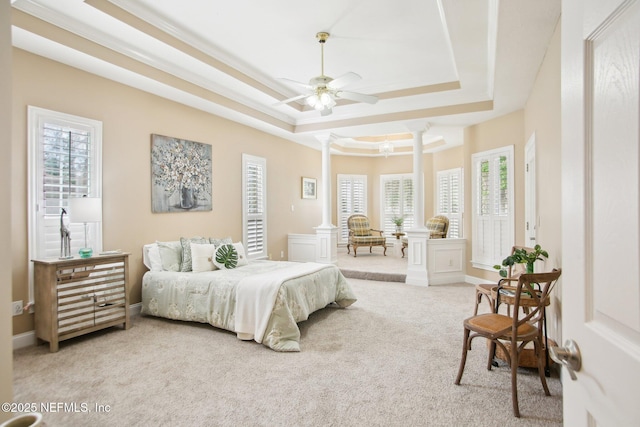 carpeted bedroom featuring crown molding, baseboards, a raised ceiling, and ornate columns