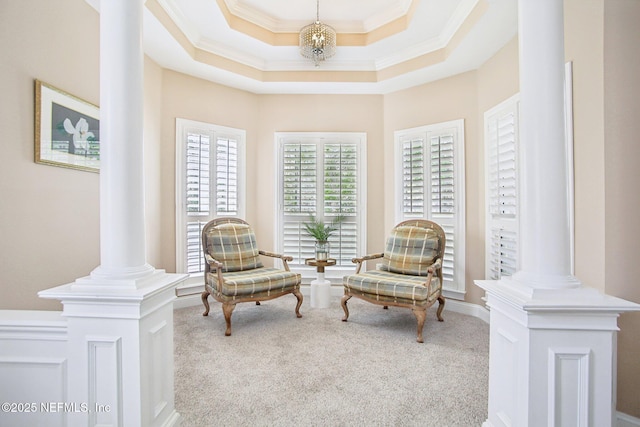 sitting room featuring a chandelier, a tray ceiling, carpet floors, ornamental molding, and decorative columns