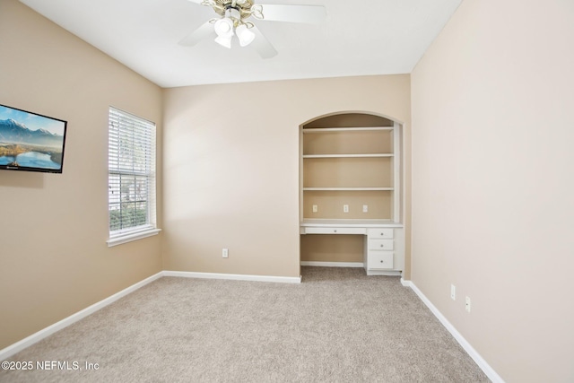 unfurnished bedroom with a ceiling fan, carpet, baseboards, and built in study area