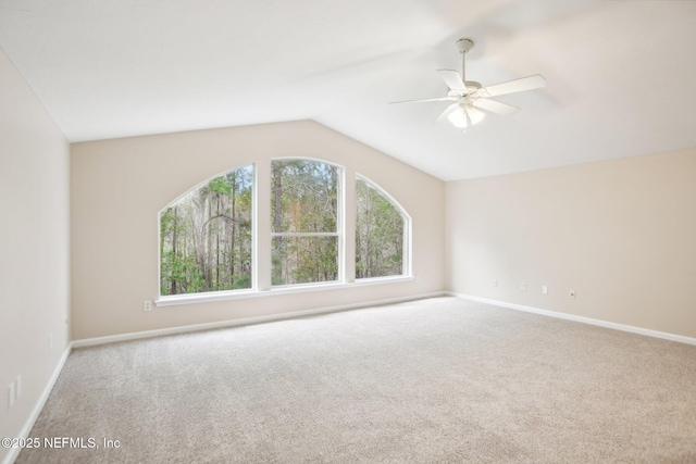 carpeted spare room featuring lofted ceiling, a ceiling fan, and baseboards