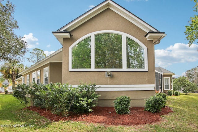 view of side of property with stucco siding and a yard