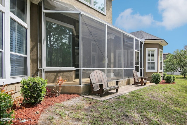 view of side of property with a yard, a sunroom, and a shingled roof