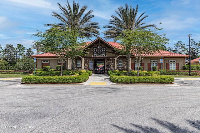 view of front facade featuring a standing seam roof, metal roof, stone siding, and stucco siding