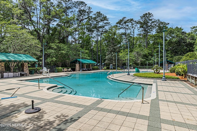 community pool with a patio area and fence