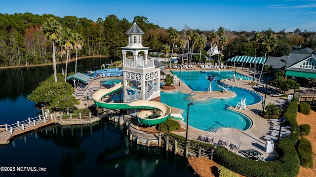 pool with a forest view, a water view, a water slide, and a patio