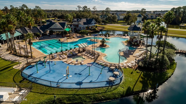 pool with a water play area, a lawn, a patio, and a water view