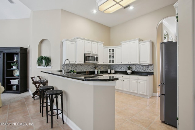 kitchen featuring dark countertops, white cabinets, appliances with stainless steel finishes, and a kitchen breakfast bar