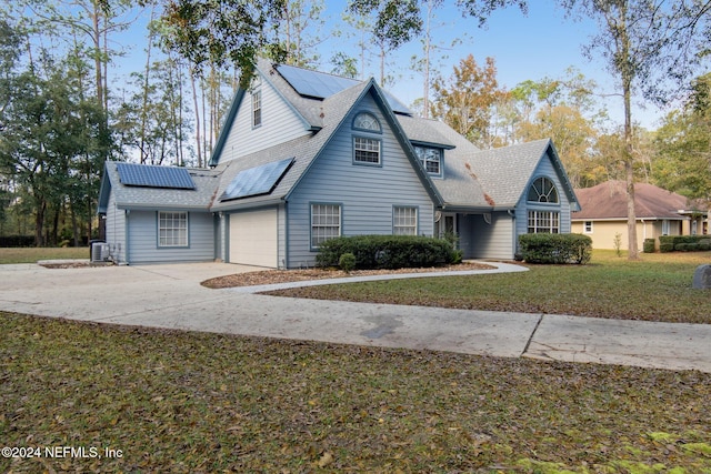 view of front facade with solar panels, a garage, a front lawn, and cooling unit